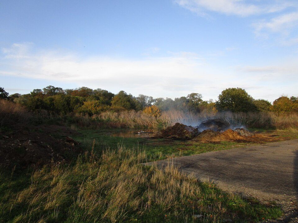 Smoky open fire burning organic waste in a rural field.