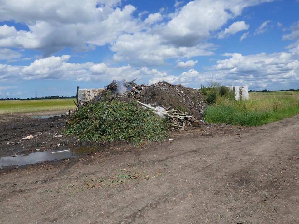 Smoking pile of brush and waste burning in open rural field.