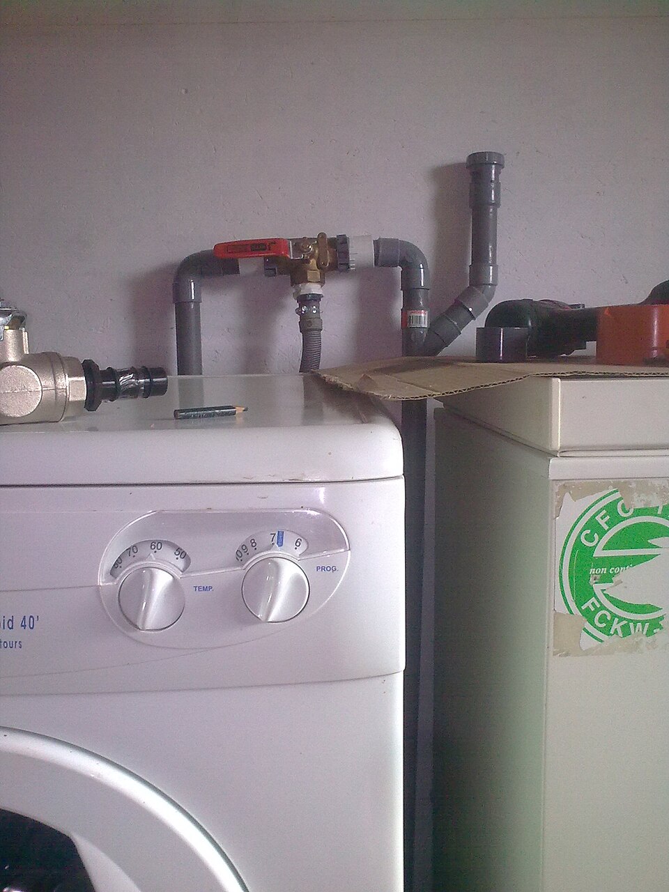 A real 3-way diverter valve with red handle plumbed into PVC pipe above a washing machine